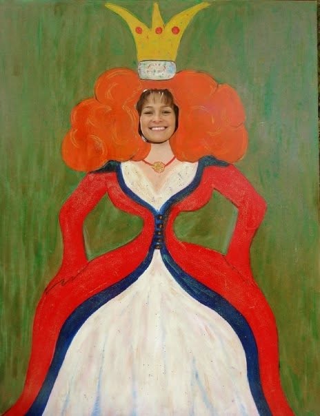 A person is playfully posing behind a painted cutout of a queen, featuring bright orange hair and a crown, with a red and white gown, against a green background.